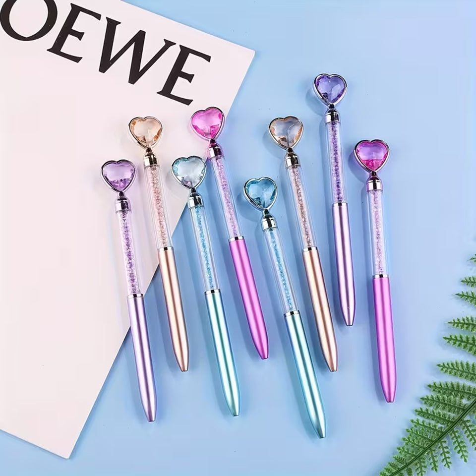 des stylos coeurs colorés dont le corps transparent renferme des strass brillants. Au but du stylo se trouve un joli coeur coloré comme s'il avait été taillé dans un diamant. L'ensemble est poétique et élégant.