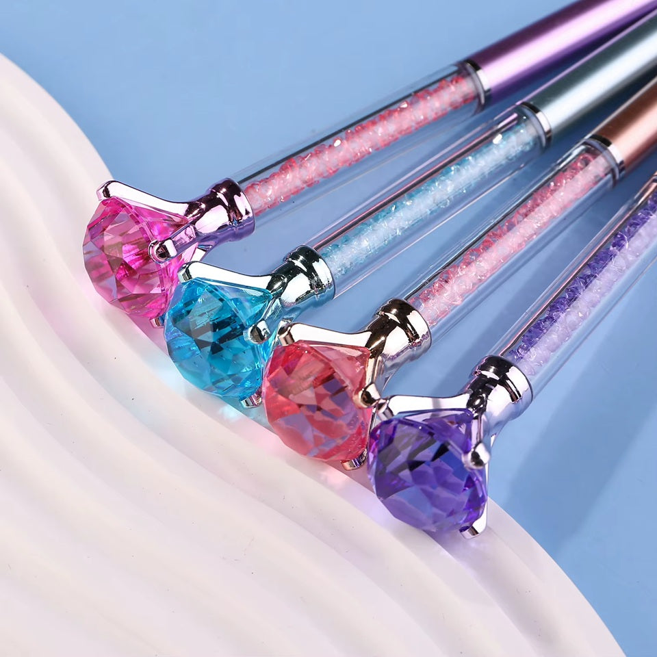de jolis stylos colorés dont le corps est transparent et renferme des strass colorés. Au bout du stylo, il y a un gros diamant coloré.