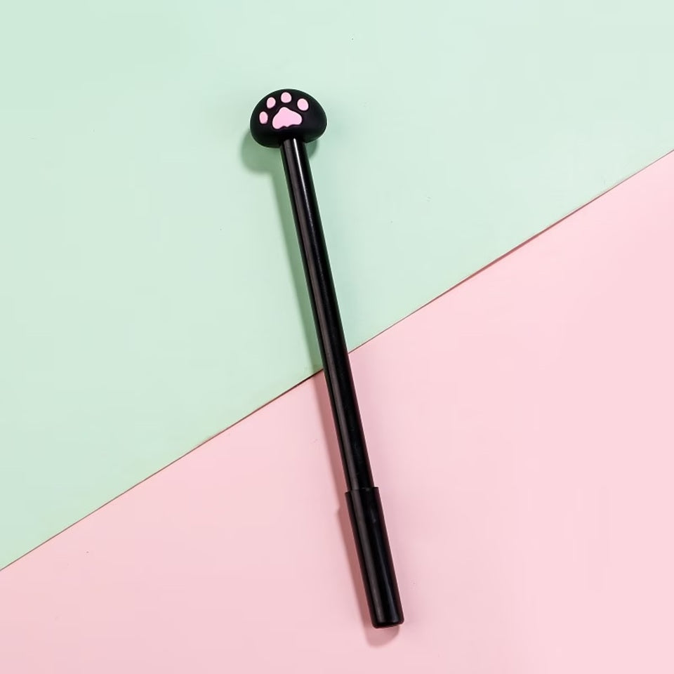 Un stylo noir dont le bout est une petite patte de chat noir et rose présenté sur un fond bicolore vert et rose pastel. Design mignon et fun.
