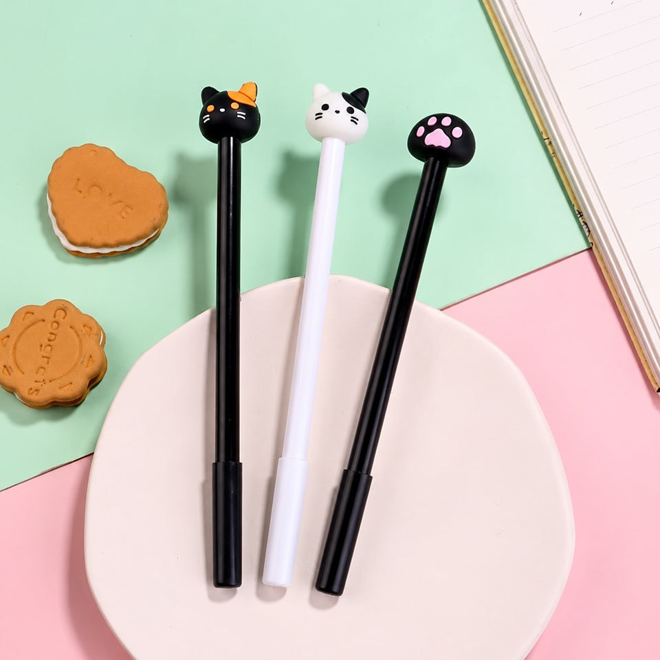 Lot de trois stylos kawaii sur le thème des chats, avec d'adorables embouts en forme de tête de chat noir, de tête de chat blanc et de patte de chat noire aux coussinets roses. Ces stylos fantaisie aux détails mignons et originaux sont présentés sur une assiette blanche, dans un décor pastel vert menthe et rose, accompagnés de petits biscuits et d'un carnet. Une papeterie kawaii idéale pour égayer une trousse, décorer un bureau ou offrir un petit cadeau aux amoureux des chats et des accessoires japonais mig