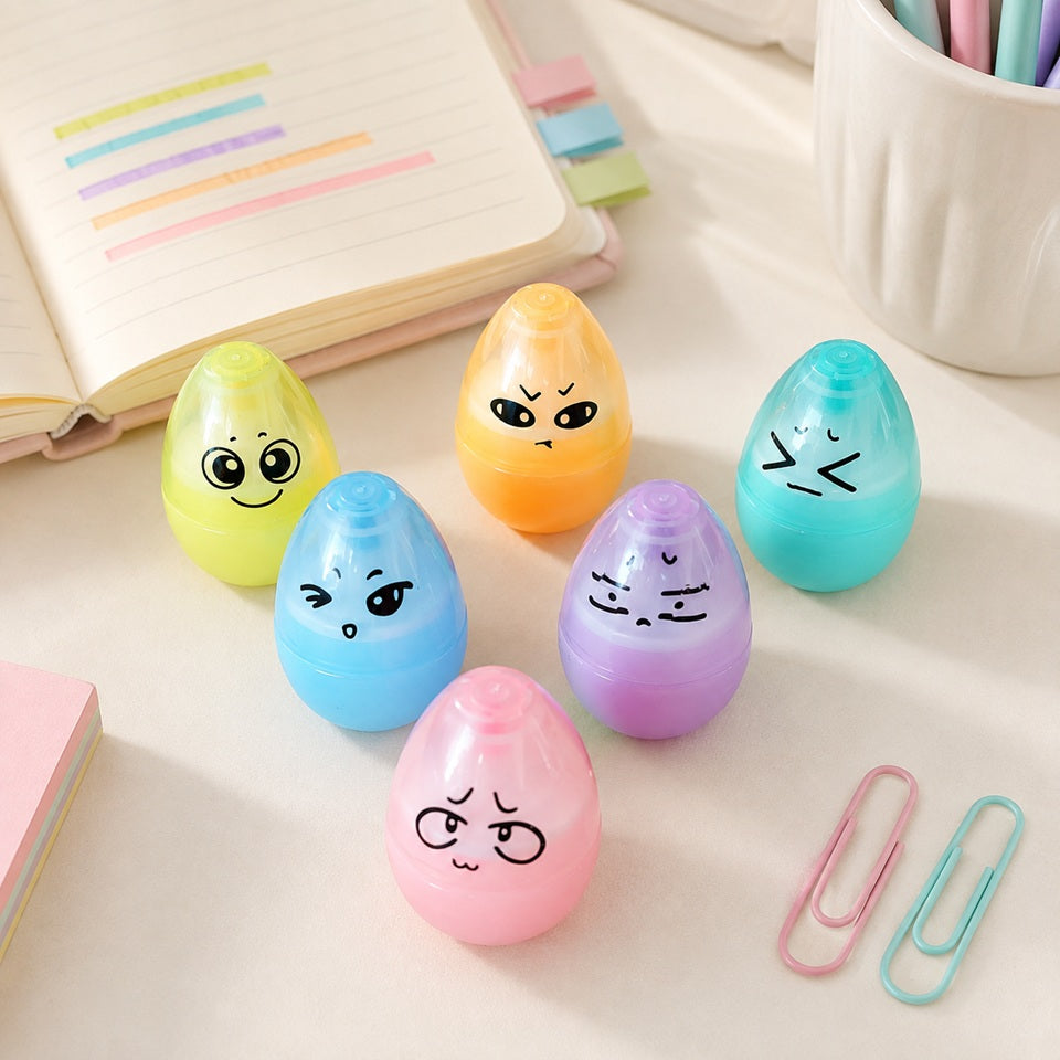 Un lot de six surligneurs en forme d’œufs kawaii aux couleurs pastel, présentés sur un bureau lumineux avec un carnet et des accessoires de papeterie.