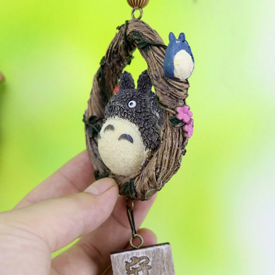 une superbe suspension inspiré de Totoro et de son univers magique et mystérieux. Totoro est dans un anneau de bois, d'où est suspendu une pancarte en bois en forme de feuille et une clochette.