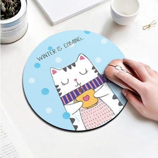 un tapis de souris rond au design d'un adorable chat qui porte une écharpe et boit un café bien chaud. Winter is coming ! Il se prépare pour rester bien au chaud pour l'hiver.
