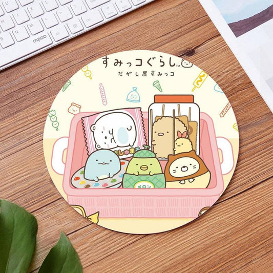 un tapis de souris rond sur les personnages de Sumikko Gurashi emballés comme des bonbons et servis sur un plateau. L'ensemble est gourmand et sucré