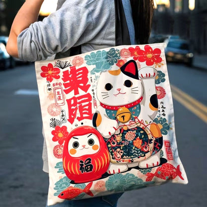 Tote bag japonais illustré d'un Maneki Neko et d'un Daruma dans des tons rouge, vert et bleu. Sac en tissu au design kawaii inspiré des porte-bonheurs traditionnels du Japon.