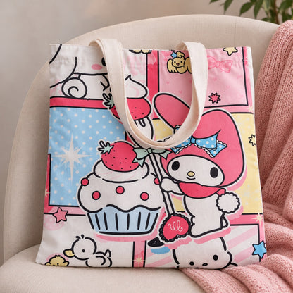 Sac tote bag My Melody kawaii aux couleurs pastel, décoré de fraises, cupcake et motifs adorables, présenté sur un fauteuil dans une ambiance douce.