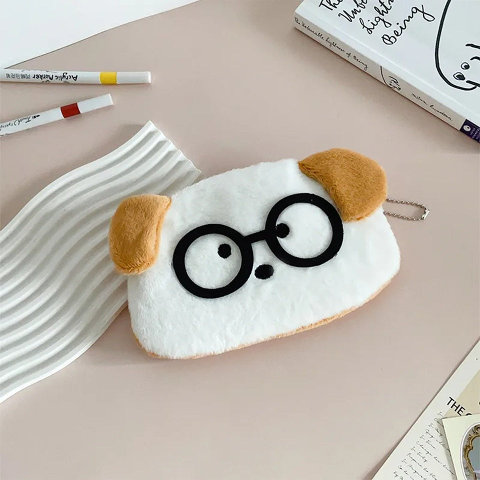 une adorable trousse toute douce en forme de chien blanc aux oreilles brunes. Il porte des lunettes noires rigolotes.