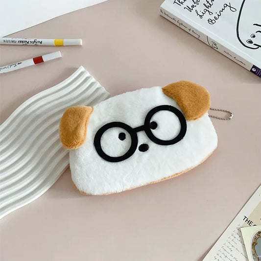 une adorable trousse toute douce en forme de chien blanc aux oreilles brunes. Il porte des lunettes noires rigolotes.