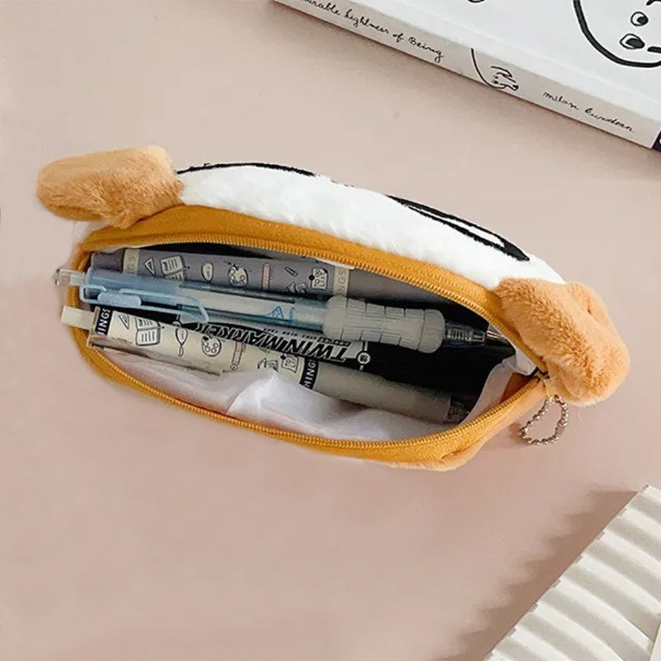 une adorable trousse toute douce en forme de chien blanc aux oreilles brunes. Il porte des lunettes noires rigolotes.