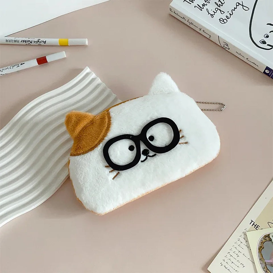 une adorable trousse toute douce en forme de chat blanc et roux. Ses petite oreilles dépassent de la trousse et ajoutent encore plus de mignonnerie. Le chat porte des lunettes noires !
