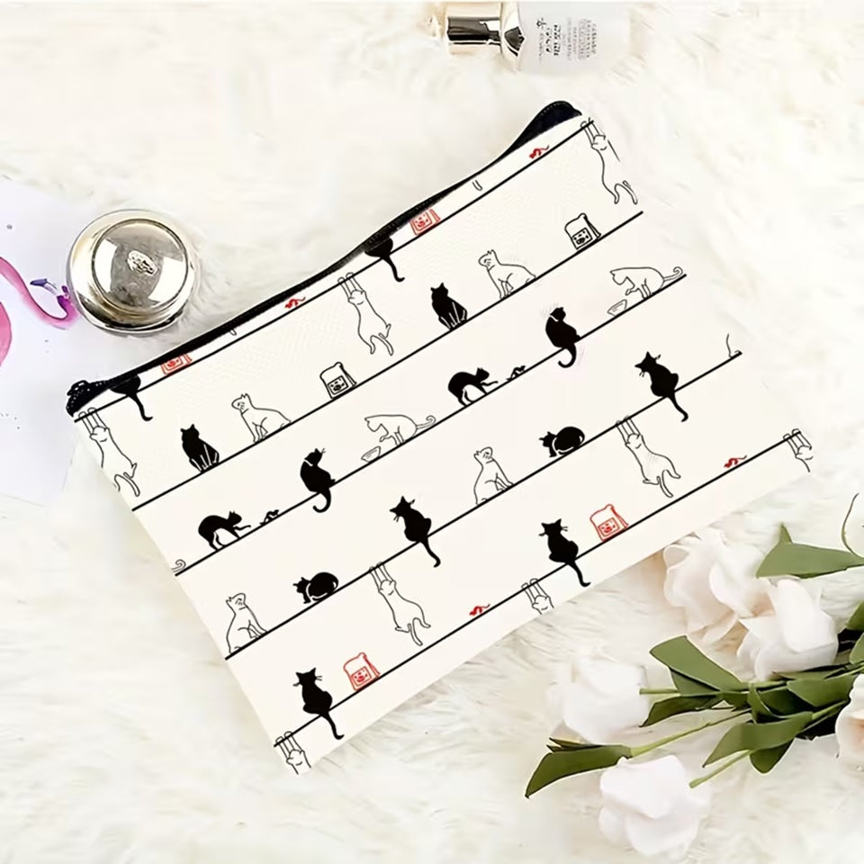 Trousse de toilette ornée d'un motif amusant de chats noirs et de chats blancs aux expressions mignonnes et rigolotes posée sur un tapis blanc et doux. Les petits félins sont représentés dans différentes poses sur un fond clair, créant un design à la fois ludique et adorable.