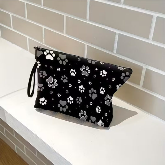 une trousse de toilette noire au motif de pattes de chat blanches et grises. Design hyper mignon et tissu doux. Idéale pour le quotidien et les vacances.