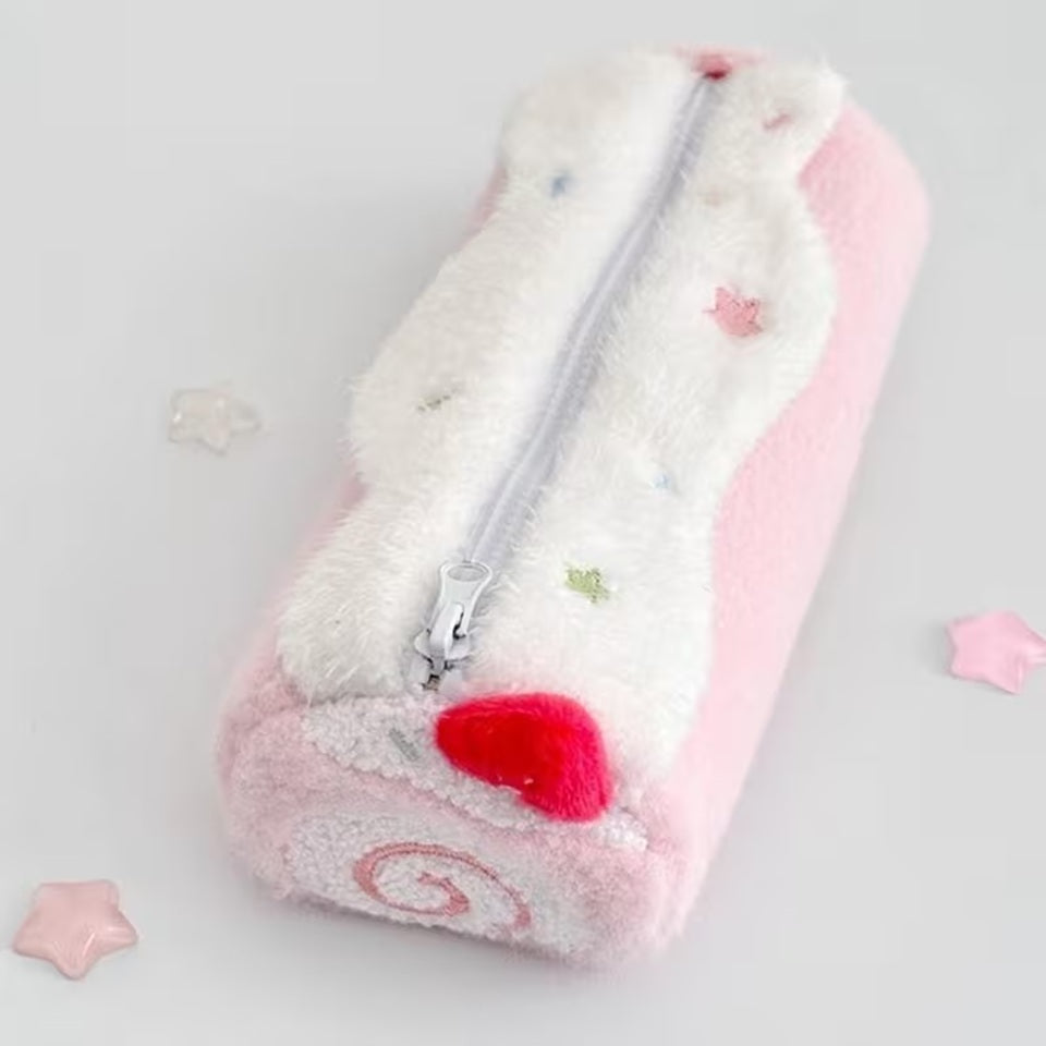 Une trousse en peluche kawaii rose pastel  posée sur une bureau blanc, entouré d'éléments kawaii. Atmosphère chaleureuse, féminine et mignonne, idéale pour une présentation de fournitures de papeterie