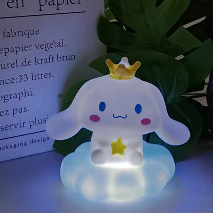 une adorable veilleuse cinnamoroll qui tient une étoile dans ses mains et qui porte une couronne jaune sur la tête. Il est assis sur un petit nuage. C'est une scène tendre. Elle diffuse de la lumière douce pour créer un effet cocooning.