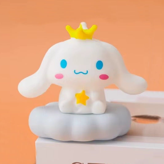 une adorable veilleuse cinnamoroll qui tient une étoile dans ses mains et qui porte une couronne jaune sur la tête. Il est assis sur un petit nuage. C'est une scène tendre. Elle diffuse de la lumière douce pour créer un effet cocooning.