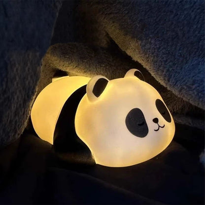 une adorable veilleuse en plastique en forme d'un petit panda allongé sur le ventre avec une expression endormie. Elle diffuse une douce lumière jaune réconfortante et calme.