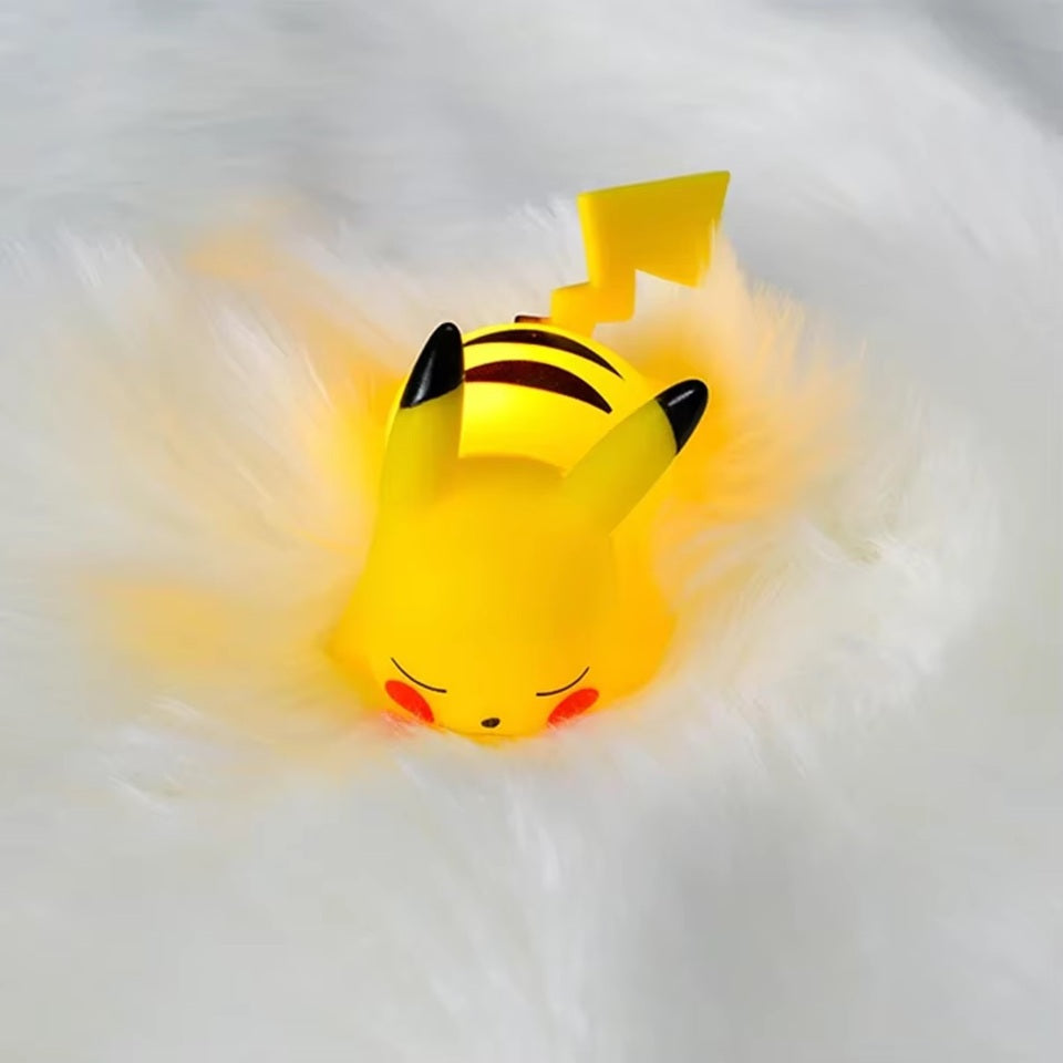 une veilleuse en forme pikachu hyper mignonne et adorable. Il dort tranquillement sur le ventre. Sa douce lumière se diffuse tendrement.