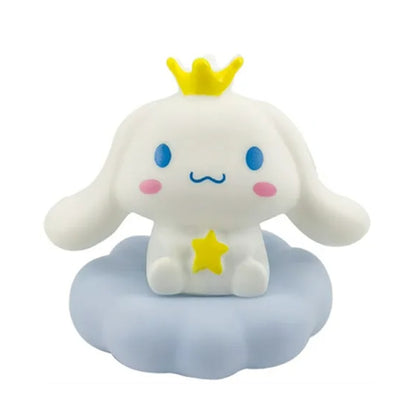 une adorable veilleuse cinnamoroll qui tient une étoile dans ses mains et qui porte une couronne jaune sur la tête. Il est assis sur un petit nuage. C'est une scène tendre. Elle diffuse de la lumière douce pour créer un effet cocooning.