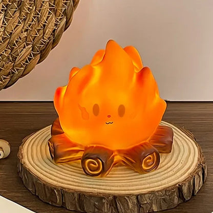une petite veilleuse adorable en forme d'un feu de camp avec ses buches et sa grosse flamme au visage expressif kawaii est posée sur un petit rondin de bois sur une table en chêne.