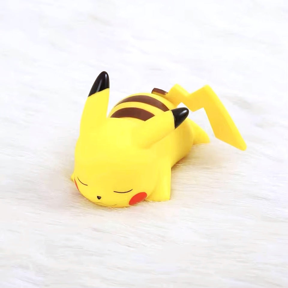 une veilleuse en forme pikachu hyper mignonne et adorable. Il dort tranquillement sur le ventre. Sa douce lumière se diffuse tendrement.
